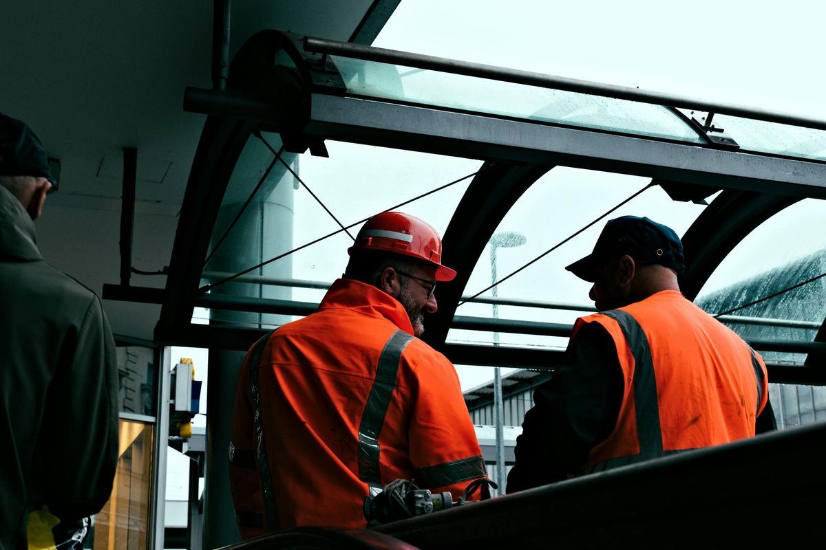 Two workers in orange coveralls and hard hats